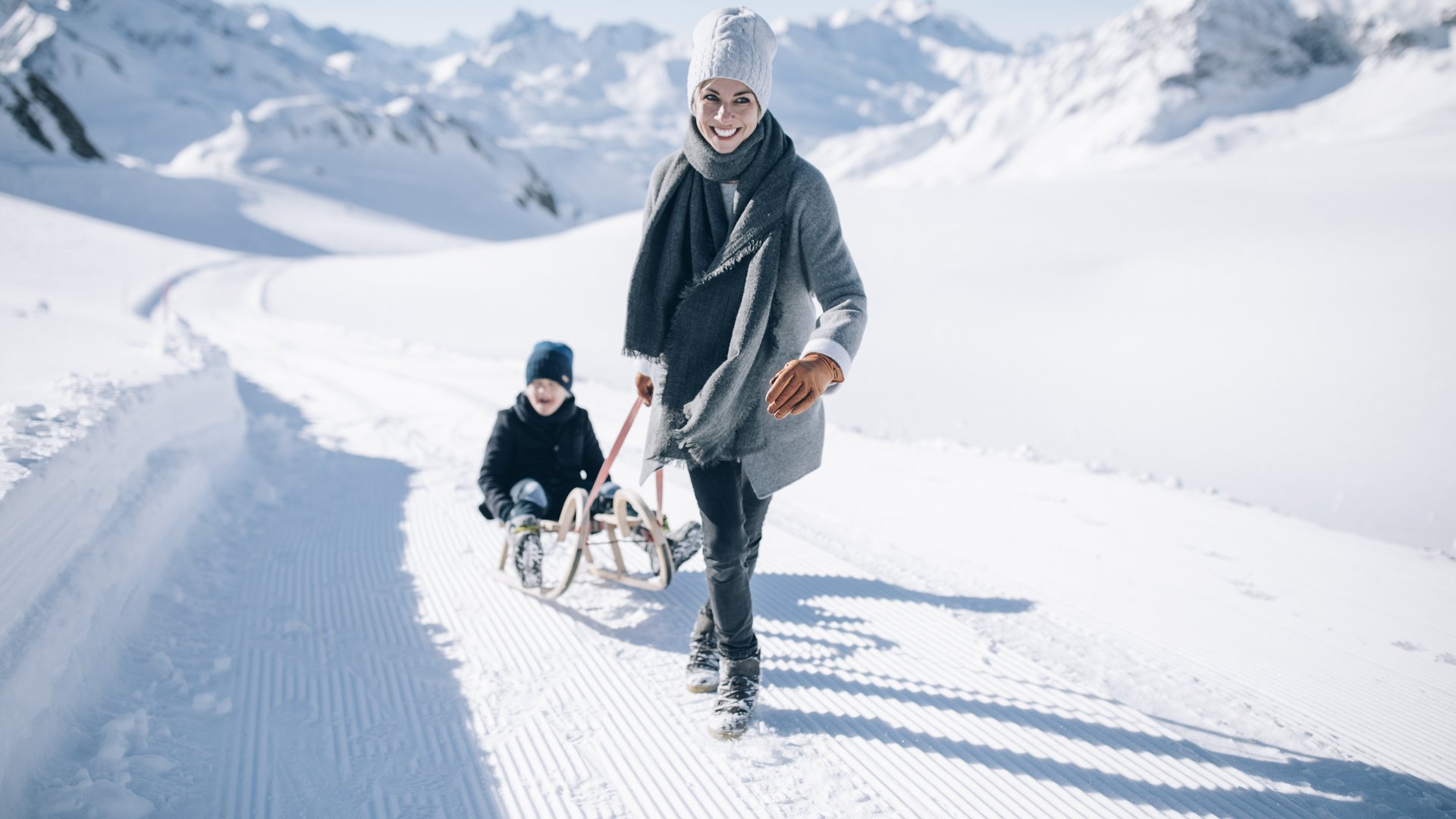 Eine Mutter zieht den Schlitten ihres Kindes durch den Arlberg © Daniel Zangerl - Lech Zürs Tourismus